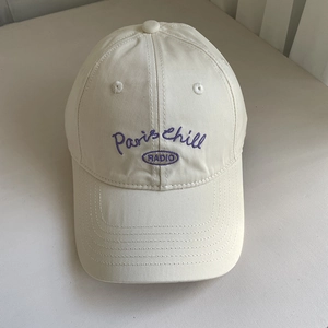 Detail of purple Paris Chill embroidery on cream cotton baseball cap with ventilation eyelets