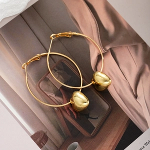 Artistic detail of gold oversized hoop earrings with heart charms on book background