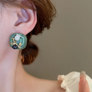 Close-up of vintage square floral stud earring with green enamel and white tulip design