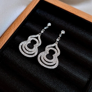 Detailed macro shot of silver hollow gourd earrings with micro-set diamonds on velvet