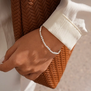 Silver beaded bracelet worn on wrist with luxury aesthetic and polished metal texture