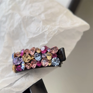 Gros plan d'une petite pince à cheveux avec strass colorés sur une base noire