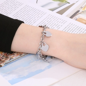 Close-up of a silver-tone chunky chain bracelet with multiple heart pendants on a wrist
