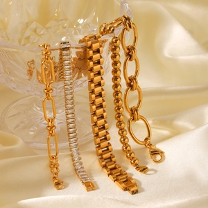 Close-up of golden stainless steel chains with zircon pavé detail over a crystal glass bowl
