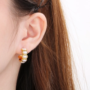 Close-up of a 18k gold-plated C-shaped stainless steel earring with white pearls on ear