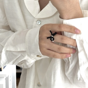 Close-up of handmade black beaded bow ring with silver bead accent on model finger