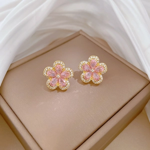 Close-up of gold-plated five-petal flower earrings with micro-set pink gemstones