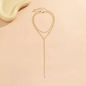Macro detail of multi-layered bohemian gold body chain with teardrop charms