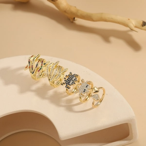 Detailed close-up of a five-piece set of gold rings with colorful zircon on a beige stand