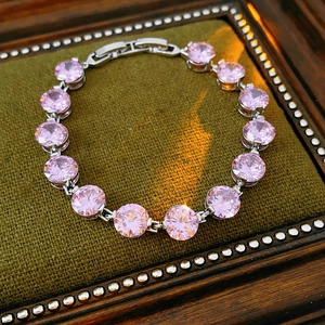Detail of pink zircon tennis bracelet with silver prong setting in vintage green velvet box