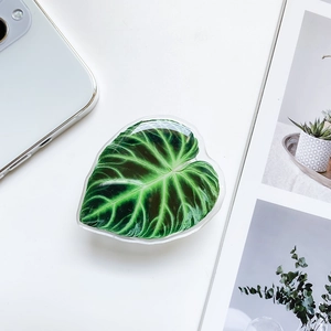 Detail of tropical leaf phone socket holder on white acrylic surface with a sleek design