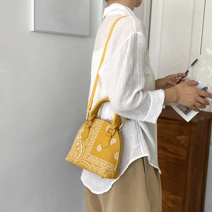 Detail of yellow shell bag featuring white Paisley print and adjustable shoulder strap