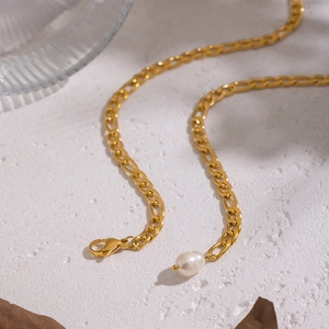 Detailed view of golden Figaro chain with freshwater pearl in elegant setting