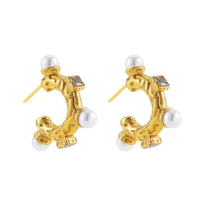 Close-up of vintage C-shape gold earrings with white pearls and clear square zircons