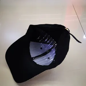 Detail view of black baseball cap with rhinestone brim, metal buckle and inner structure