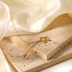 Close-up of golden hollow star pendant with inlaid crystals on elegant silk background