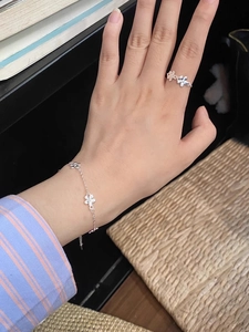 Detail of silver floral bracelet and ring set worn on hand with minimalist daisy design