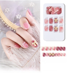 Detail of pink cat-eye press-on nails with 3D bows and pearls on a white display