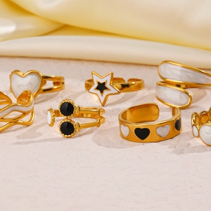 Close-up of gold stainless steel rings with black and white enamel heart and star patterns