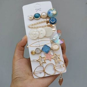 Detail of candy color hair clip set featuring pearls and resin charms held in hand