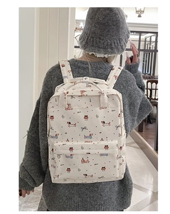 Detailed back view of a beige canvas backpack featuring cute dachshund and bow patterns