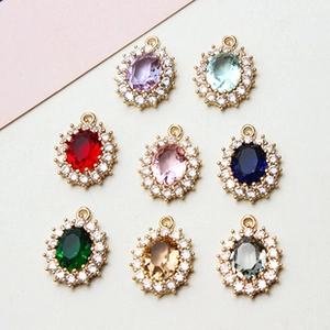 Detailed view of colorful oval gemstone pendants with gold plating and white crystal halo