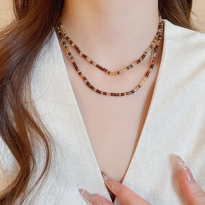 Close-up of double-layer beaded necklace with brown and beige glass beads on model
