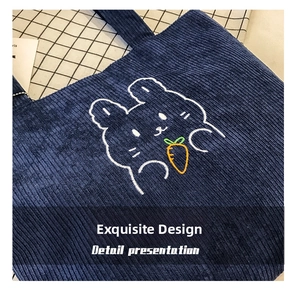 Detail of navy blue corduroy tote bag featuring a cute white rabbit with orange carrot embroidery