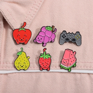 Detailed view of six cat-fruit enamel pins on pink denim, including strawberry and apple designs