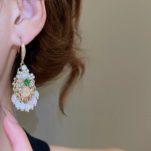 Close-up of vintage gold drop earrings featuring teardrop crystals and floral gemstone details