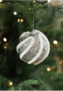 Detail einer silbernen Glitzer-Weihnachtskugel mit weißem Wellenmuster am Tannenbaum