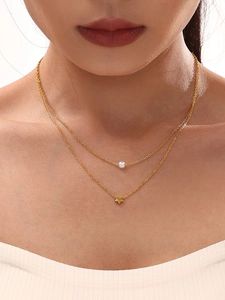Close-up of double-layer gold star and pearl necklace on model for stacked look