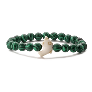 Macro shot of malachite beaded stretch bracelet with a white dolphin charm on white background