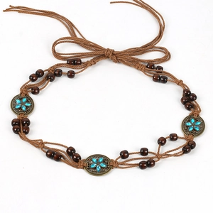 Detail of bohemian braided rope belt with turquoise floral metal plates and wooden beads
