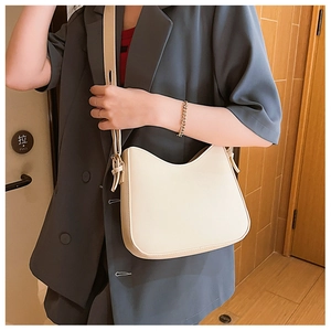 Sac bandoulière demi-lune blanc cassé porté avec détail de bandoulière réglable