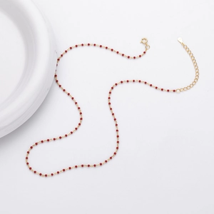 Close-up of S925 sterling silver hallmark on gold chain with red beads detail