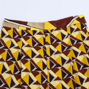 Dettaglio dei pantaloni con motivo geometrico nei colori giallo e marrone su tessuto