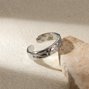 Macro detail of silver liquid metal open ring displayed on a natural raw stone