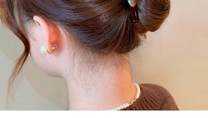 Detailed view of elegant pearl hair claw and matching necklace on a model's low bun