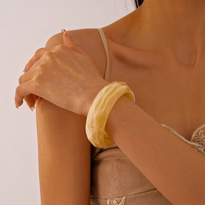 Macro detail of amber marble pattern acrylic bangle showing wide band texture and warm tones