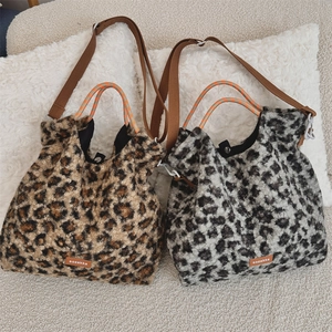 Détail de sacs en peluche léopard avec poignées tressées et écusson de la marque
