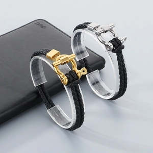Close-up of black braided leather bracelets with gold and silver horseshoe buckle details