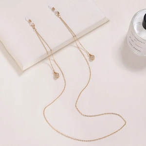 Détail de la chaîne à lunettes dorée avec cristaux en goutte et boucles en silicone