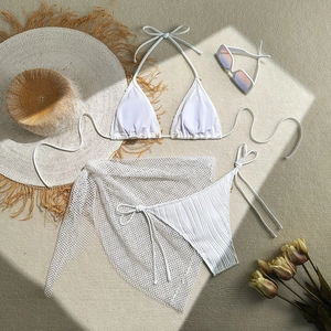 Flat lay of white three-piece bikini set with starfish tassels and mesh cover-up skirt