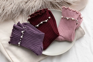 Detail of ribbed knit socks with ruffled edges and pearl studs in purple and red