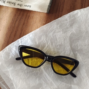 Close-up of cat-eye kids sunglasses featuring a black resin frame and yellow tinted lenses