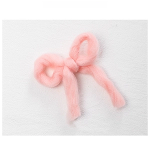 Macro shot of a pink plush felt bow ornament with soft wool-like fiber texture