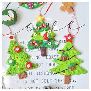 Detailed view of handmade green clay Christmas tree ornaments with festive bows and stars