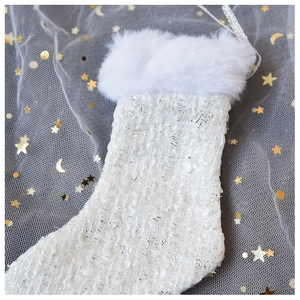 Detail of tweed Christmas stocking featuring white faux fur trim and silver hanging loop