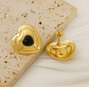 Detail view of vintage heart earrings with gold plating and black enamel on stone base